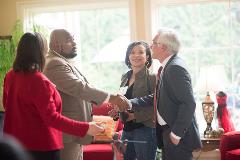 A group of people having a conversation and two men shaking hands